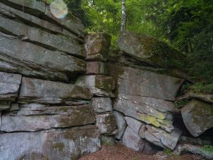 Large, weathered rock formations covered in moss and lichen, surrounded by lush greenery and trees.