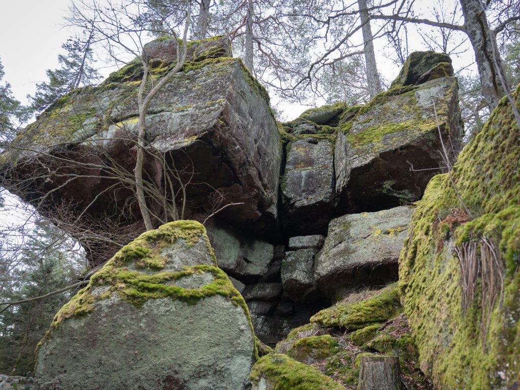 Large moss-covered boulders nestled among trees, with a prominent rock formation appearing to balance above.